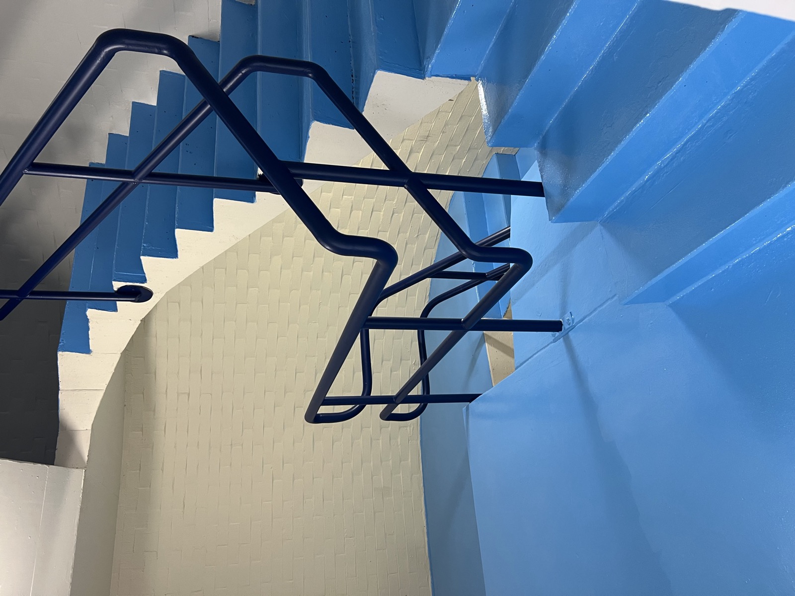 Freshly painted blue commercial stairwell with navy handrails in Perth